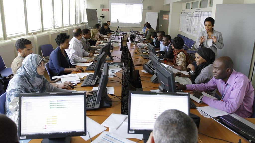 Professionals working in a modern office with multiple computer workstations